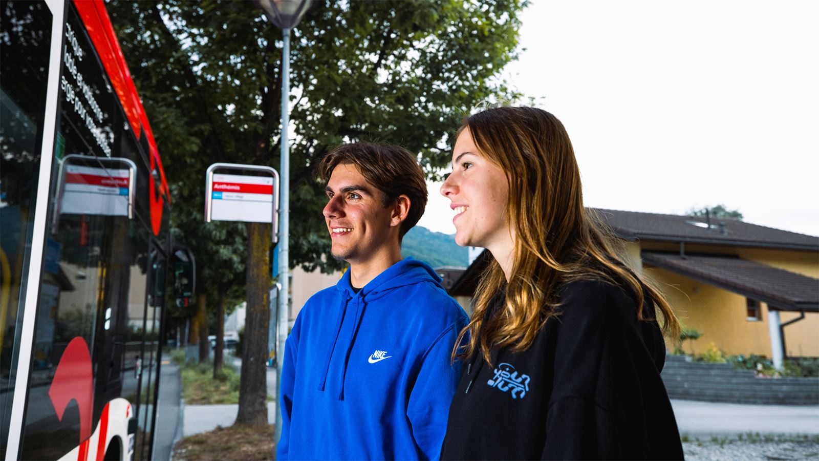 Ein junges Paar steigt abends aus einem Bus.