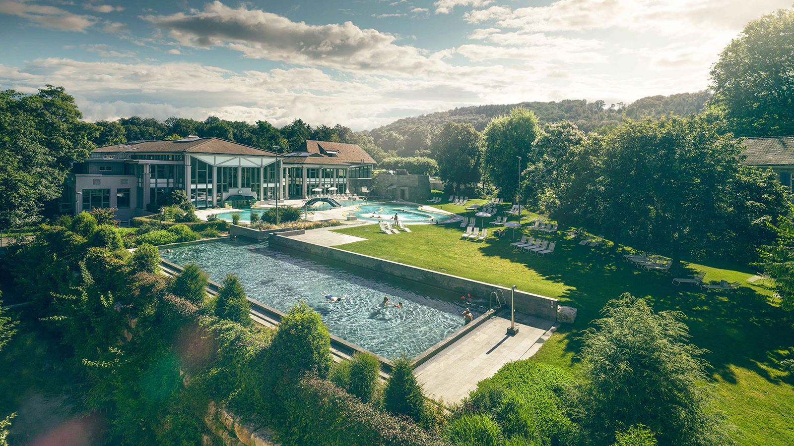 Large swimming pool in the park with houses in the background.