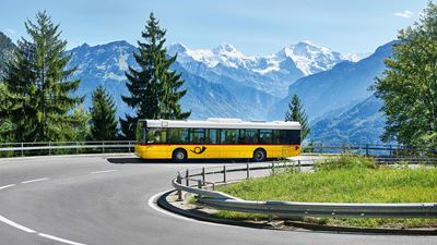 Ein Postauto fährt Richtung Beatenberg. Im Hintergrund Eiger, Mönch und Jungfrau.
