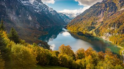 Lake Klöntal surrounded by snow-covered mountains in an autumnal atmosphere.