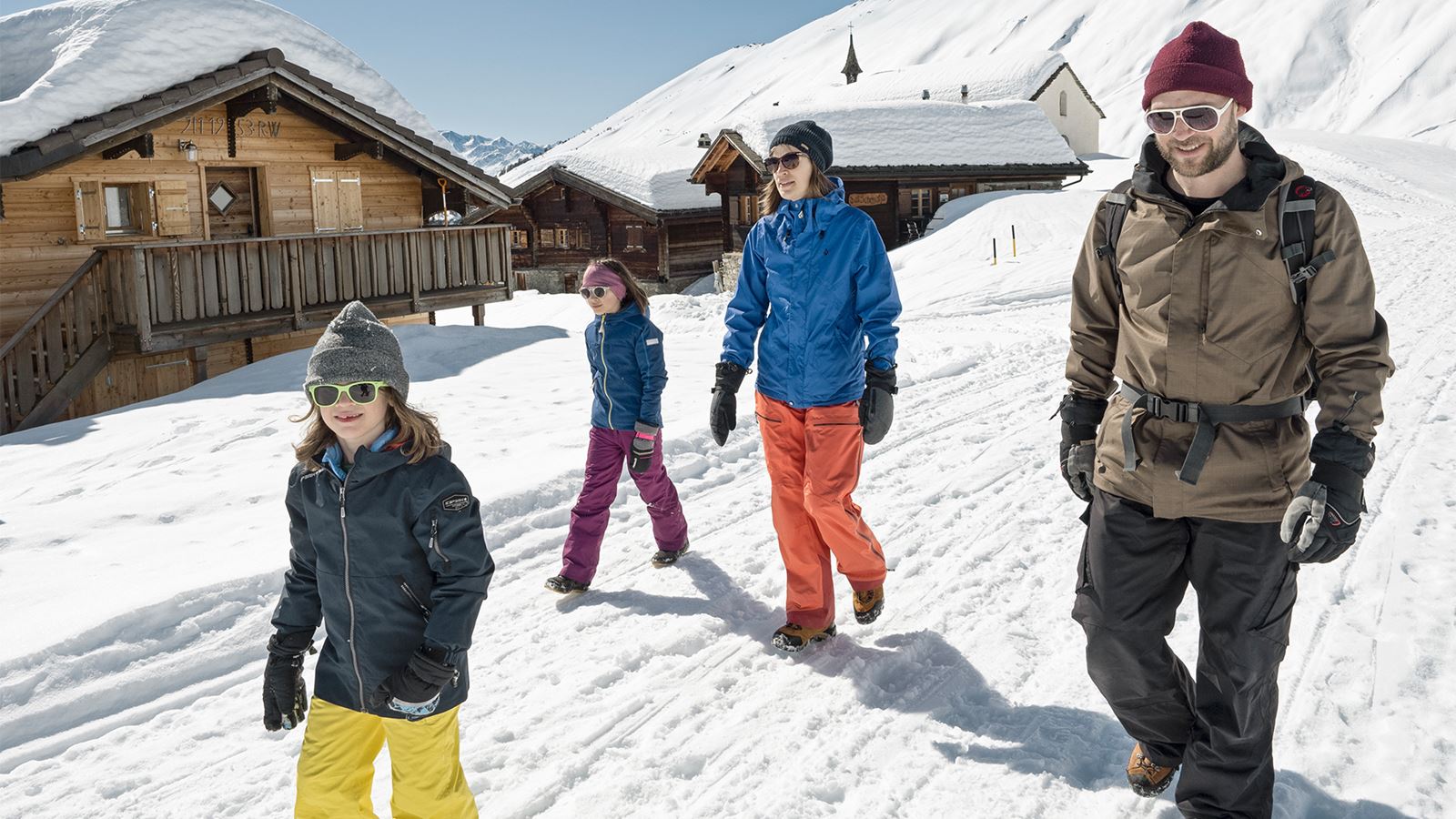 Une famille part en randonnée en montagne par une belle journée d’hiver.