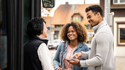Eine Postauto Fahrerin im Gespräch mit zwei Fahrgästen