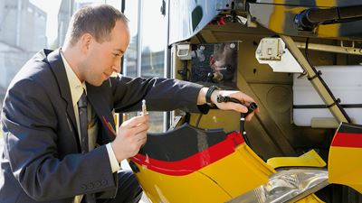 A Postbus driver changing a defective light bulb