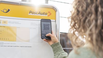 Scannen eines QR-Codes an einer Postauto Haltestelle