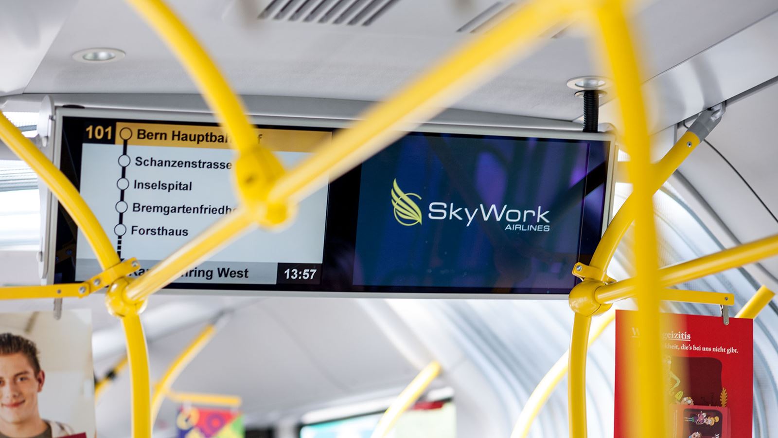 Two screens can be seen inside a Postbus. One screen shows the stops on this line and the other shows advertising.