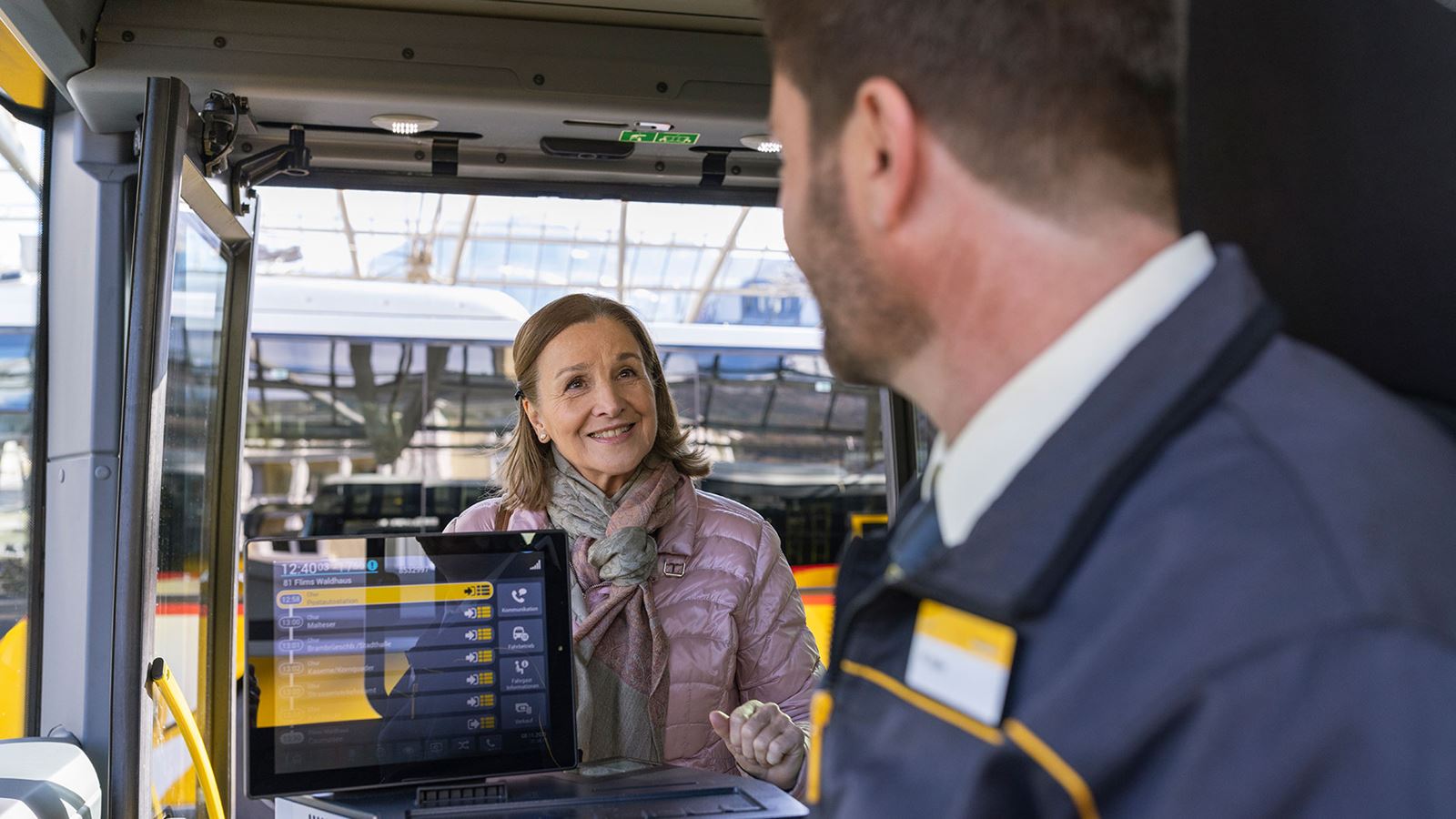 Une femme monte à bord du car postal et le chauffeur l’accueille chaleureusement.