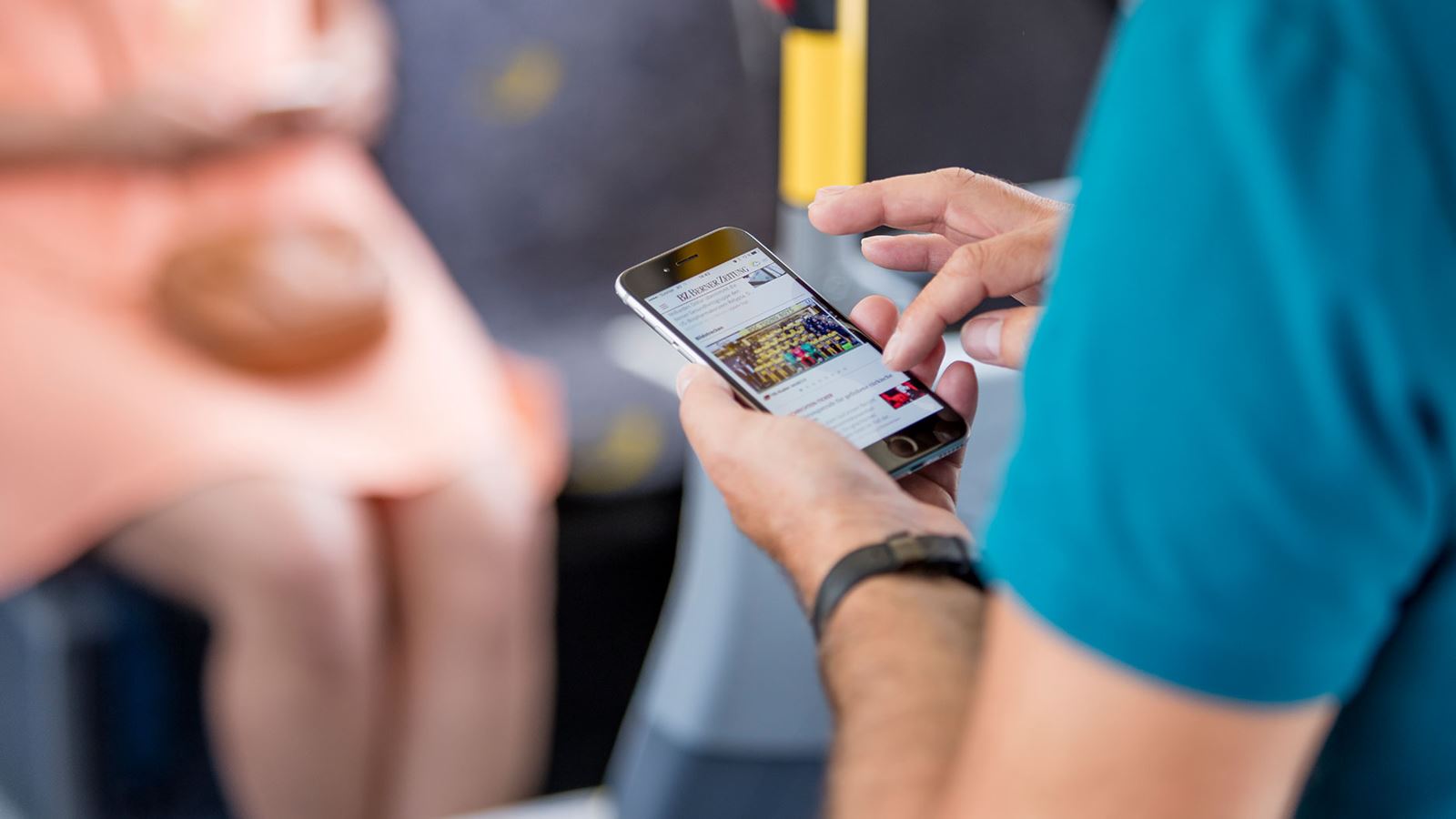 A passenger surfs the PostBus WiFi on his mobile phone.