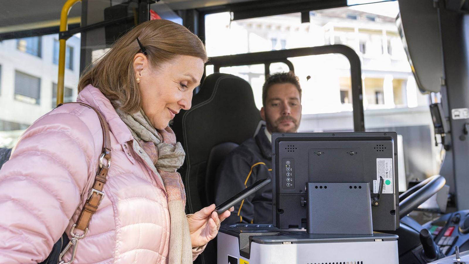 Una donna compra il biglietto salendo sull’autopostale e guarda il suo smartphone.