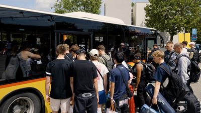 A group of people at an event board a waiting Postbus